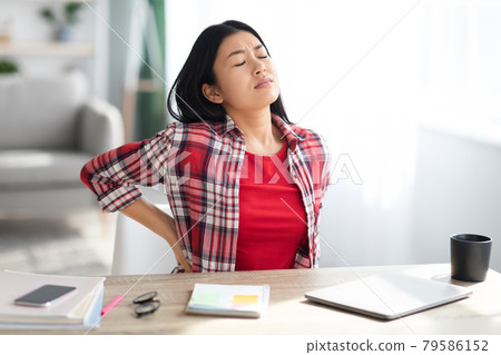 Beautiful Young Asian Woman Suffering From Backache While Working In Home Office Beautiful Young Asian Woman Suffering From Backache While Working In Home Office 79586152