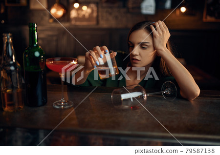 Drunk woman drinks alcohol at counter in bar 79587138