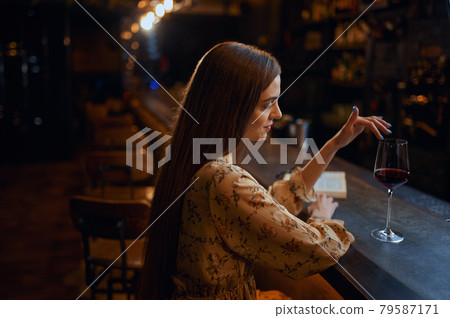 Alone woman with glass of wine sitting in bar Alone woman with glass of wine sitting in bar 79587171