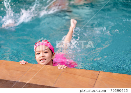 Young asian girl in swimsuit smiling in swimming pool, active summer vacation concept. 79590425