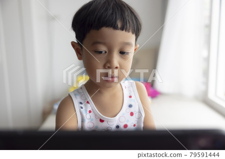 close-up, Asian boy studying through online e-learning system. Have video call distant class with teacher using tablet at home, Covid-19 coronavirus, study online on computer, homeschooling concept close-up, Asian boy studying through online e-learning system. Have video call distant class with teacher using tablet at home, Covid-19 coronavirus, study online on computer, homeschooling concept 79591444