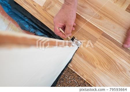 Caucasian man installing wood parquet board during flooring work Caucasian man installing wood parquet board during flooring work 79593664