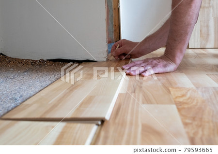 Caucasian man installing wood parquet board during flooring work Caucasian man installing wood parquet board during flooring work 79593665