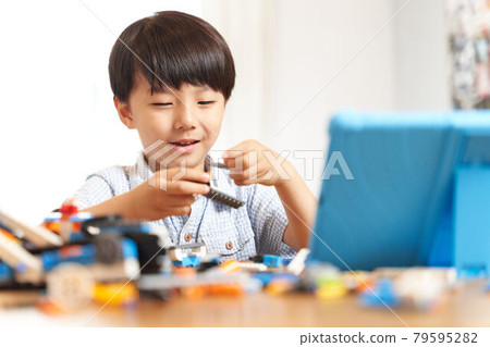 一個男孩一邊看平板電腦一邊組裝編程材料 79595282