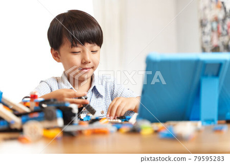 一個男孩一邊看平板電腦一邊組裝編程材料 79595283