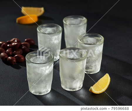 Icy shot glasses of vodka with lemon and olives 79596688