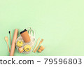 Reusable wooden cutlery, cork mug and grocery bag with apples. Dishwashing brush and kraft wrapping paper, eco friendly fork, knife, spoon on green backdrop. Zero waste concept. Copyspace, flatlay. 79596803