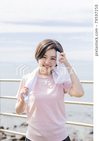 年輕女子慢跑時用毛巾擦汗 年輕女子慢跑時用毛巾擦汗 79597258