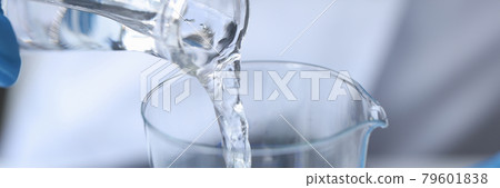 Clear liquid is poured from glass bottle 79601838