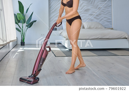 Woman in lingerie uses vacuum cleaner in hot weather. Woman in lingerie uses vacuum cleaner in hot weather. 79601922