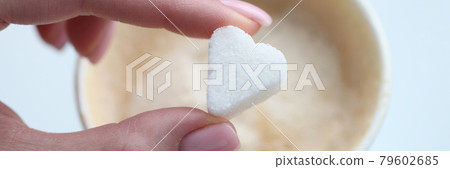 Woman putting coffee sugar cube in shape of heart closeup 79602685