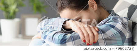 Sad woman sitting with her head bowed on sofa 79602727