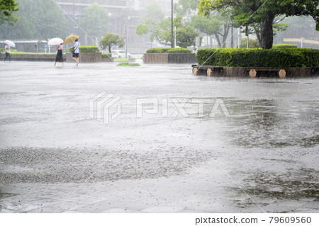 A city with heavy rain, people walking with an umbrella 79609560