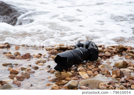 DSLR camera on stone beach wet from water sea wave DSLR camera on stone beach wet from water sea wave 79610054