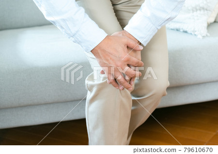 Middle-aged man holding his knee Middle-aged man holding his knee 79610670