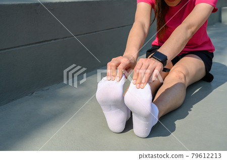 Runner woman trying to do foot stretching for prevent injuries. The benifit of stretching can increasing flexibility performance and reduce risk of injury. Runner woman trying to do foot stretching for prevent injuries. The benifit of stretching can increasing flexibility performance and reduce risk of injury. 79612213