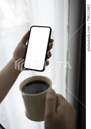 Close up view man holding cup of hot coffee and using mobile phone. Close up view man holding cup of hot coffee and using mobile phone. 79612963