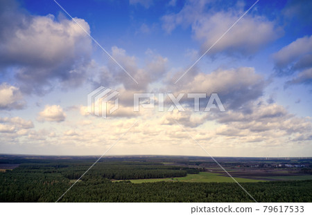 Blue sky with white clouds over the cultural landscape in the north of Germany with forests, meadows and fields, aerial view with the drone Blue sky with white clouds over the cultural landscape in the north of Germany with forests, meadows and fields, aerial view with the drone 79617533