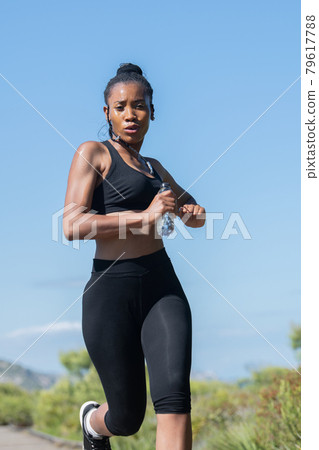 Low shot of afro american woman in sports clothes running: Exercise and strength concept. 79617788