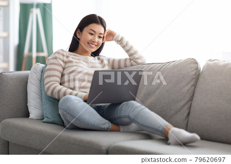 Happy Young Asian Woman Watching Movies Online On Laptop At Home Happy Young Asian Woman Watching Movies Online On Laptop At Home 79620697