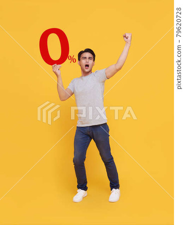 Young handsome Asian man holding up to 0% and happy celebrating on yellow background for no interest installment payment concept. 79620728