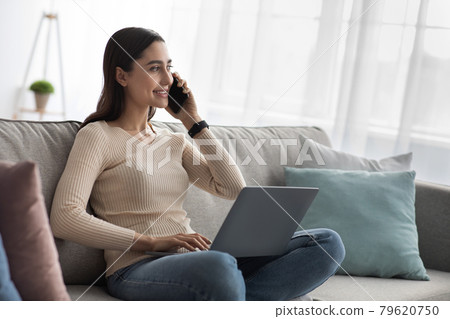 Female speaking on mobile phone with client, use laptop for remote work at home, new normal 79620750