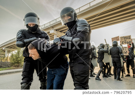 Riot police twisting man at rally 79620795
