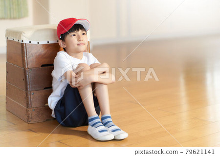 一個男孩靠在一個跳馬箱上坐著 79621141