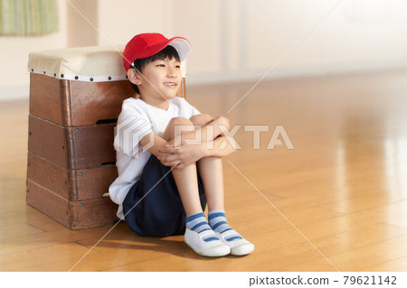 一個男孩靠在一個跳馬箱上坐著 79621142