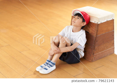 一個男孩靠在一個跳馬箱上坐著 79621143