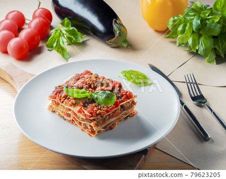 Piece of lasagna on white plate with knife and Piece of lasagna on white plate with knife and 79623205