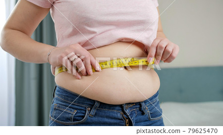 Overweight woman with tape measure around waist. Stock Photo by