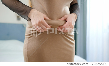 Closeup of obese woman in dress holding fat folds on belly Closeup of obese woman in dress holding fat folds on belly 79625513