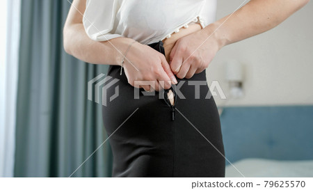 Young obese woman trying to fit and zip up tight small dress. Concept of excessive weight, obese female, dieting and overweight problems Young obese woman trying to fit and zip up tight small dress. Concept of excessive weight, obese female, dieting and overweight problems 79625570