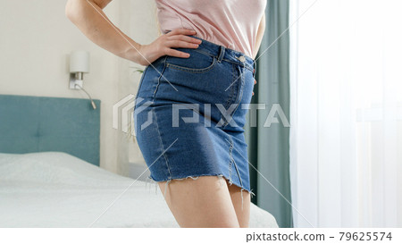 Sexy slim woman in short denim skirt dressing in bedroom Sexy slim woman in short denim skirt dressing in bedroom 79625574