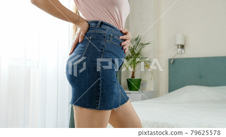 Beautiful slim woman dressing in sexy jeans skirt in bedroom. 79625578