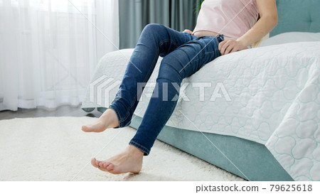 Young woman with wide hips and obese thighs sitting on bed and putting on jeans. Concept of excessive weight, obese female, dieting and overweight problems Young woman with wide hips and obese thighs sitting on bed and putting on jeans. Concept of excessive weight, obese female, dieting and overweight problems 79625618