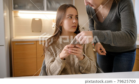 Mother shouting and getting angry because of teenage daughter using smartphone all day. Gadget addiction and family conflict 79625700