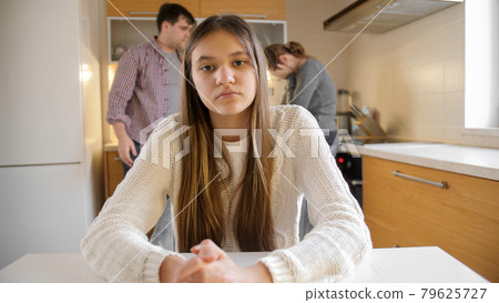Teenage girl looking in camera while parents arguing and having conflict on kitchen. Family violence, conflicts and relationship problems Teenage girl looking in camera while parents arguing and having conflict on kitchen. Family violence, conflicts and relationship problems 79625727