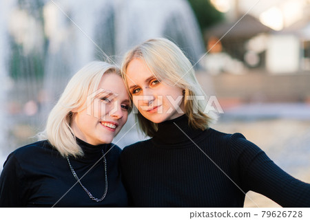 Two young females walking smiling embracing and kissing outdoor in the city Two young females walking smiling embracing and kissing outdoor in the city 79626728