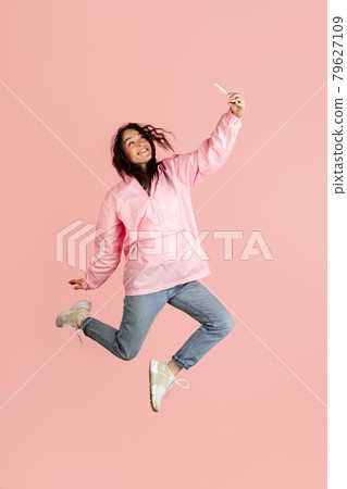 Young pretty Caucasian woman with smartphone in her hand jumping isolated over light pink background with copyspace. 79627109