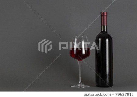 Red wine bottle and glass on a gray background. Wine drinking culture concept. Red wine bottle and glass on a gray background. Wine drinking culture concept. 79627915