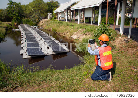 An Asian Engineers investigating floating solar panels Renewable Solar Power Plant. An Asian Engineers investigating floating solar panels Renewable Solar Power Plant. 79628026