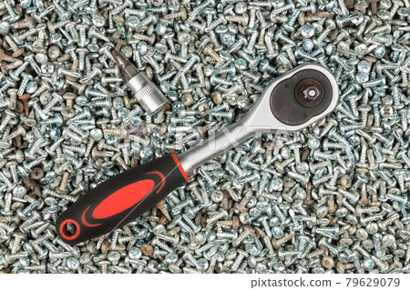 Screwdriver is lies on a pile of screws. Tools, screws made of steel. Industrial background. 79629079
