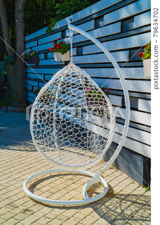 hanging chair cocoon on the frame in the yard of the house.  79634702