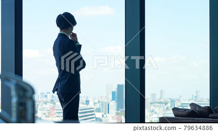 A businessman looking at the city from the window 79634886