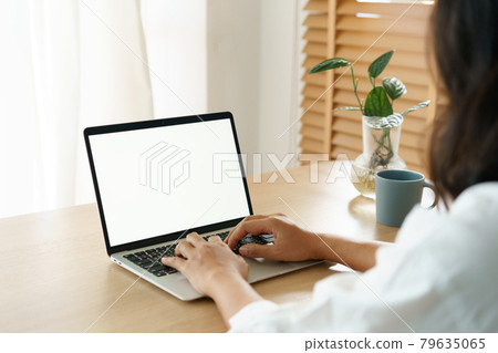 Blank digital computer laptop white screen, Asian women typing work from home via shoulder close up 79635065