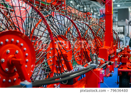 Red tractor rotary wheel hay and tedding rakes at farming exhibition Red tractor rotary wheel hay and tedding rakes at farming exhibition 79636480