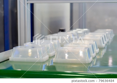 Empty food containers on conveyor belt of plastic injection molding machine Empty food containers on conveyor belt of plastic injection molding machine 79636484