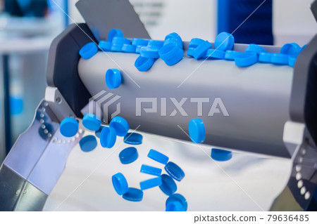 Production line - many blue plastic bottle caps falling from conveyor belt 79636485